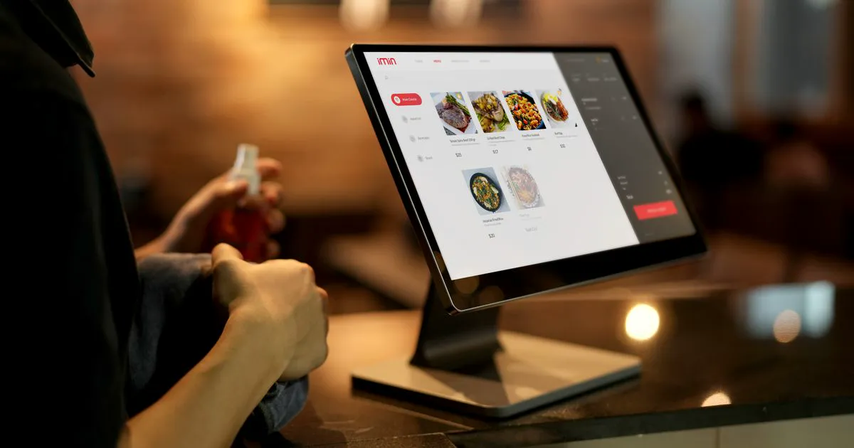 A restaurant counter touchscreen ordering kiosk displaying a food menu